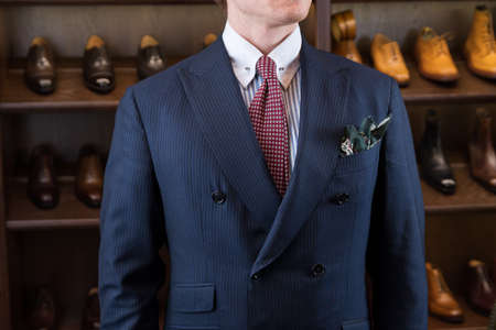 Man in classic fashion suit against luxury shoes boutique store display with variety of different modelsの写真素材