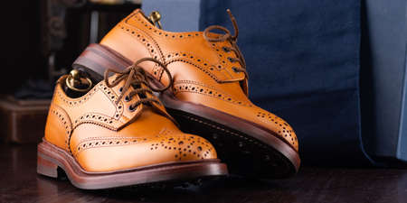 Brown full grain leather brogues on wooden display in in men shoes boutique store with box and cloth shoe bags.の写真素材