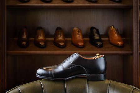 Black full grain leather shoe in front of wooden display in men shoes boutique store.の写真素材