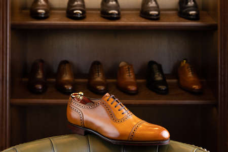 Brown full grain leather shoe in front of wooden display in men shoes boutique store.の写真素材