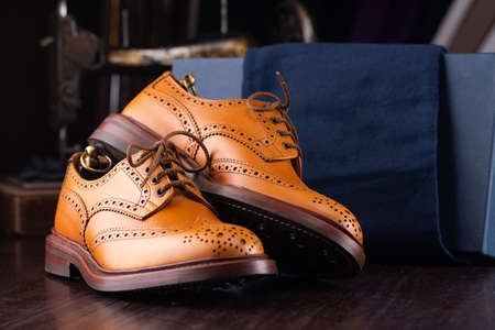 Brown full grain leather brogues on wooden display in in men shoes boutique store with box and cloth shoe bags.の写真素材