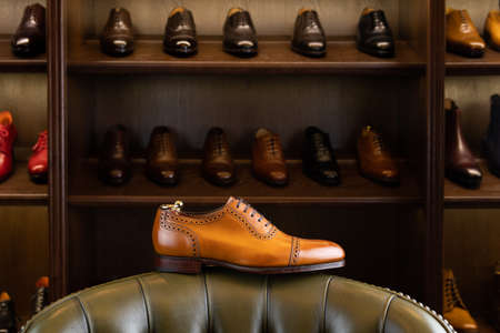 Brown full grain leather shoe in front of wooden display in men shoes boutique store.の写真素材
