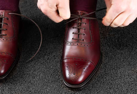 Trying new shoes. Man is putting on a new pair of luxury burgundy full grain leather shoes at footwear storeの写真素材