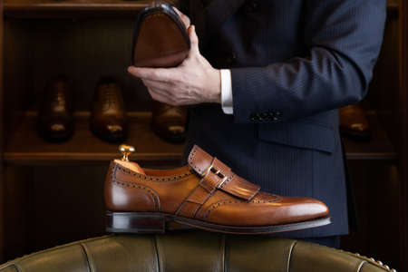 Brown full grain leather shoe in front of wooden display in men shoes boutique store.の写真素材