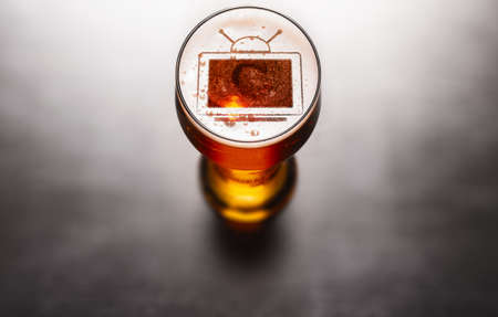 Beer and TV concept. Television symbol on beer glass foam on black table, view from aboveの写真素材