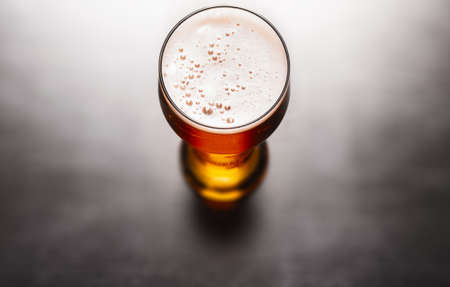 Glass of frothy fresh beer on tableの写真素材
