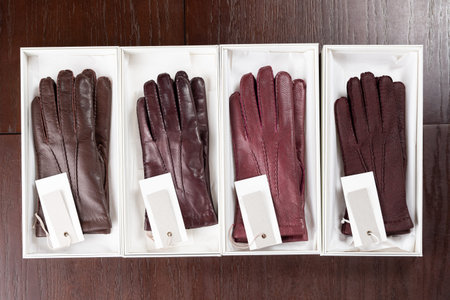 Burgundy leather gloves in boxes at luxury clothing boutique store.