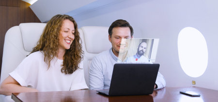 Making video conference call with colleague on laptop HUD hologram on board of private jet....