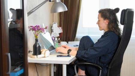 Woman working on laptop from home due to coronavirus self isolation. Authentic home workplace. Coronavirus outbreak 2020.の写真素材