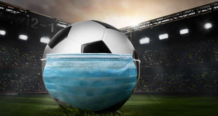 Play safe. Soccer or football ball wearing mask on stadium during coronavirus outbreak.の写真素材