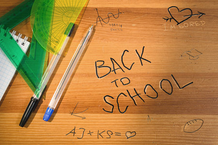Back to school writing on wooden desk. Top view of school table with supplies and accessories....