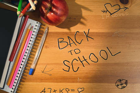Back to school writing on wooden desk. Top view of school table with supplies and accessories. Shadow and sun beam overlay.の写真素材