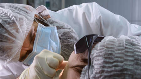 Suturing stitches. Oral surgeon performing surgery installing implant into senior woman mouth. Dentist works with a patient in modern dental clinicの写真素材