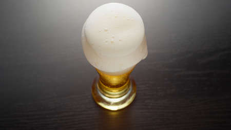 Glass of frothy fresh beer on tableの写真素材