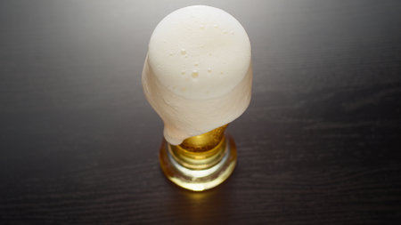 Glass of frothy fresh beer on tableの写真素材