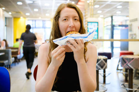 Woman eating in fast food restaurantの写真素材