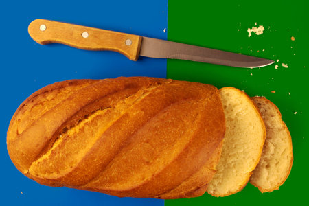 Breadsliced loaf of bread and a knife on a blue-green background