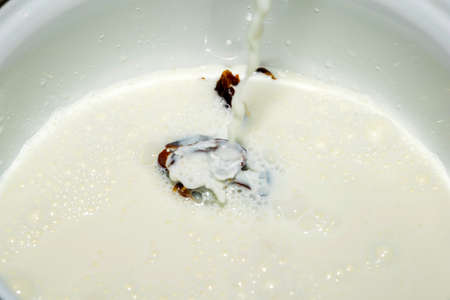 Hushaf - date milk, a traditional dish of Ramadan, cooking, ingredients, seedless dates lying in the saucepan pouring a stream of milkの写真素材
