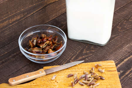 Hushaf - date milk, traditional ramadan dish, cooking, ingredients, pitted dates in a plate, knife and seeds on a cutting board and milk in the bottle stand on a wooden tableの写真素材