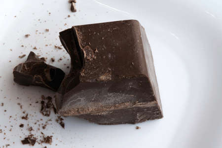 a large chopped piece of chocolate lies on a white ceramic plateの写真素材