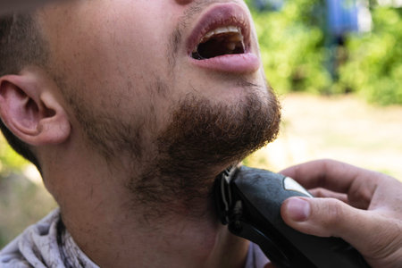 the barber cuts his beard to the guy with a shearing machine