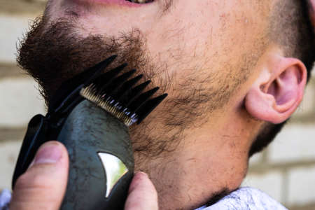 the barber cuts his beard to the guy with a shearing machineの写真素材