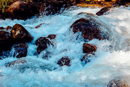 the water of a stormy mountain river flowing among stones and bouldersの写真素材