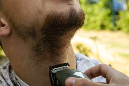 the barber cuts his beard to the guy with a shearing machineの写真素材