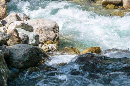 the water of a stormy mountain river flowing among stones and bouldersの写真素材