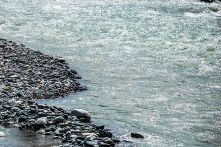 the water of a stormy mountain river flowing among stones and bouldersの写真素材