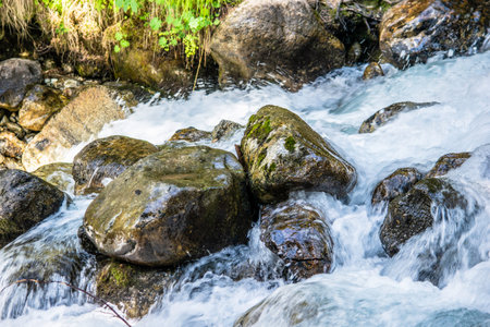 the water of a stormy mountain river flowing among stones and boulders