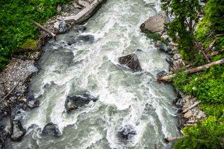 the water of a stormy mountain river flowing among stones and bouldersの写真素材