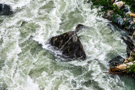 the water of a stormy mountain river flowing among stones and boulders