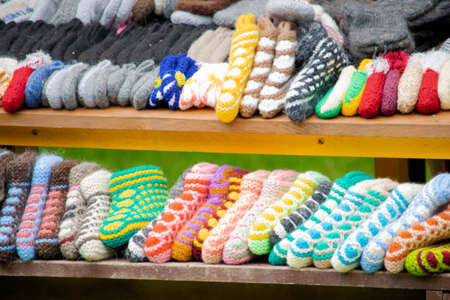handmade multi-colored knitted socks and slippers lie on the window of a street marketの写真素材
