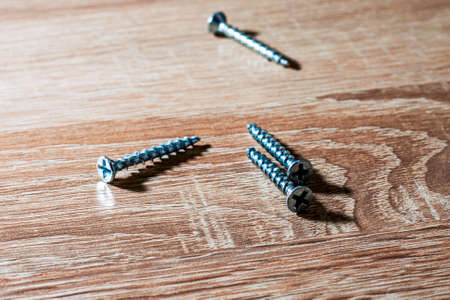 metal screws lying on a wooden tableの写真素材