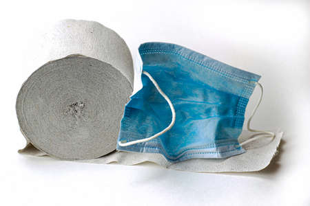 concept pandemic symbols covid 19 medical hygiene mask and toilet paper roll on white backgroundの写真素材