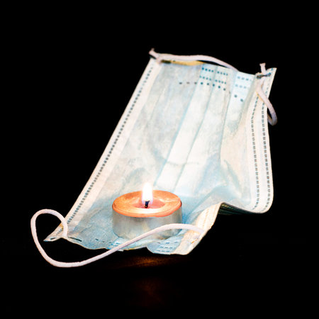 covid19 virus epidemic victims memory concept burning candle and medical hygiene dressing on black...