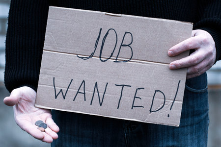 the unemployed person holds in his hand a cardboard tablet with the inscription job wanted in his...