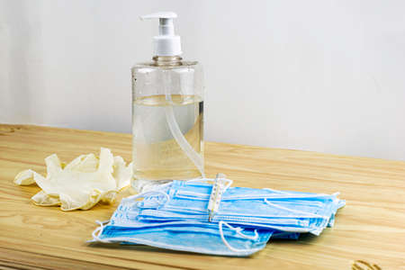 medical protective hygiene masks, rubber gloves, thermometer and a sanitizer in a transparent bottle are on the tableの写真素材