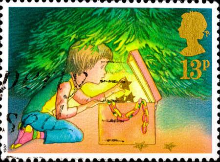 02 10 2020 Divnoe Stavropol Territory Russia postage stamp Great Britain 1987 Christmas Decorating the Christmas Tree boy takes out Christmas decorations from a boxのeditorial素材