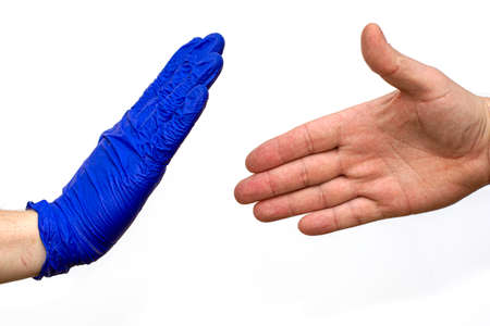 a chick of a man in a blue medical glove stops an unprotected hand trying to greet himの写真素材
