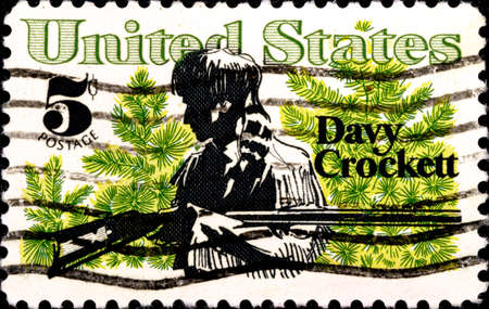 02 10 2020 Divnoe Stavropol Territory Russia postage stamp USA 1967 American Folklore Davy Crockett and Scrub Pine man with a gun on a background of green branchesのeditorial素材