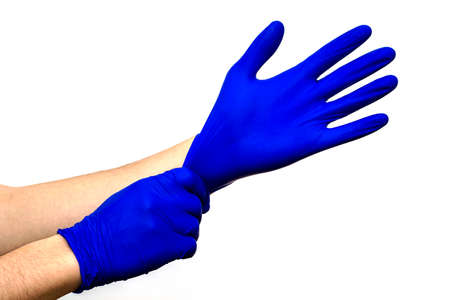 man puts on his hands blue surgical rubber protective gloves on a white backgroundの写真素材