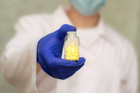 bubble with yellow pills in the doctor s hand. doctor in the background in blurの写真素材
