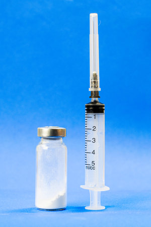 syringe and ampoule with medicine on a blue background vertically standing