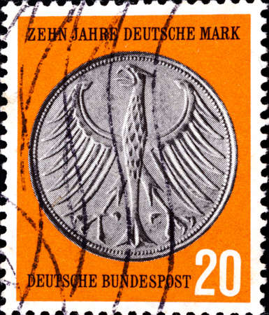 02 10 2020 Divnoe Stavropol Territory Russia Germany postage stamp 1958 The 10th Anniversary of the D-mark Coat side of a 5-DM piece orange backgroundのeditorial素材