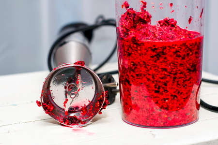 mixer high-speed shaft and ground redcurrant in a mortar on a wooden tableの写真素材