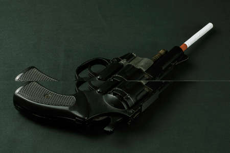 concept of harm to smoking, smoking kills, cigarette sticks out of gun barrel on dark background