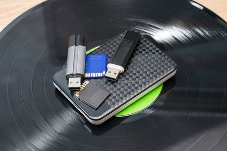 modern storage media hard drive and flash cards lie on an old gramophone record