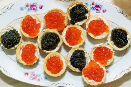 bread baskets with butter stuffed with red and black caviar lie on a plateの写真素材